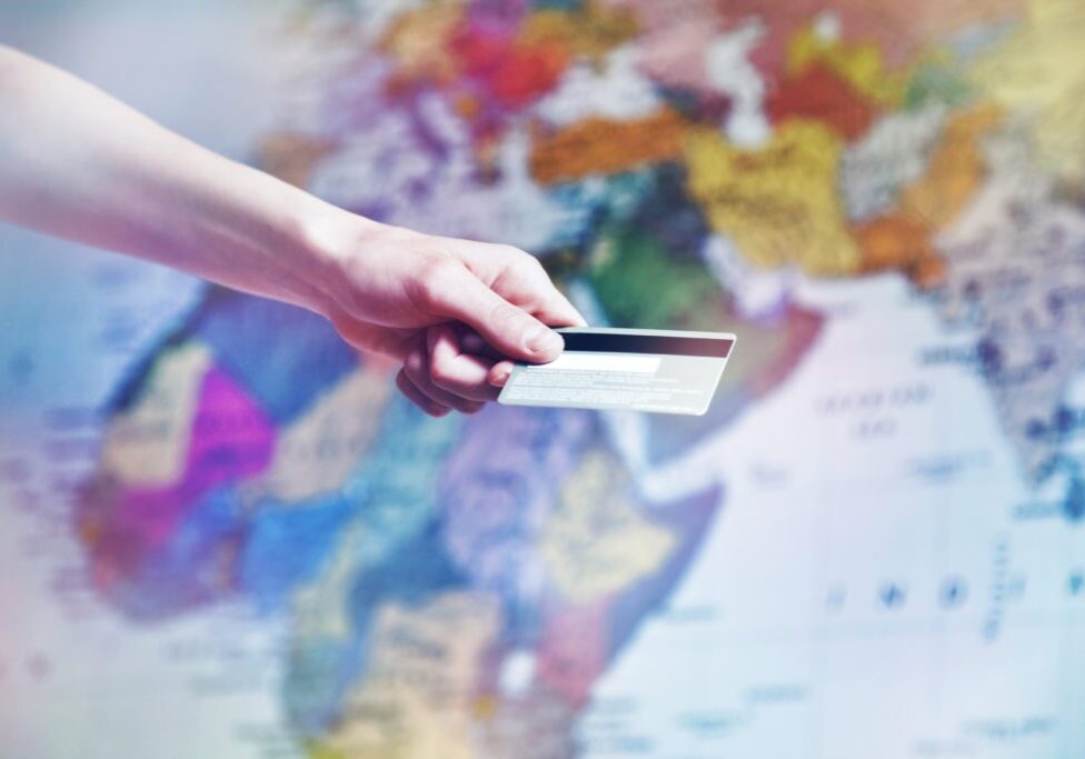 Hand,Holding,Credit,Card,On,World,Map,Background.,Online,Shopping,